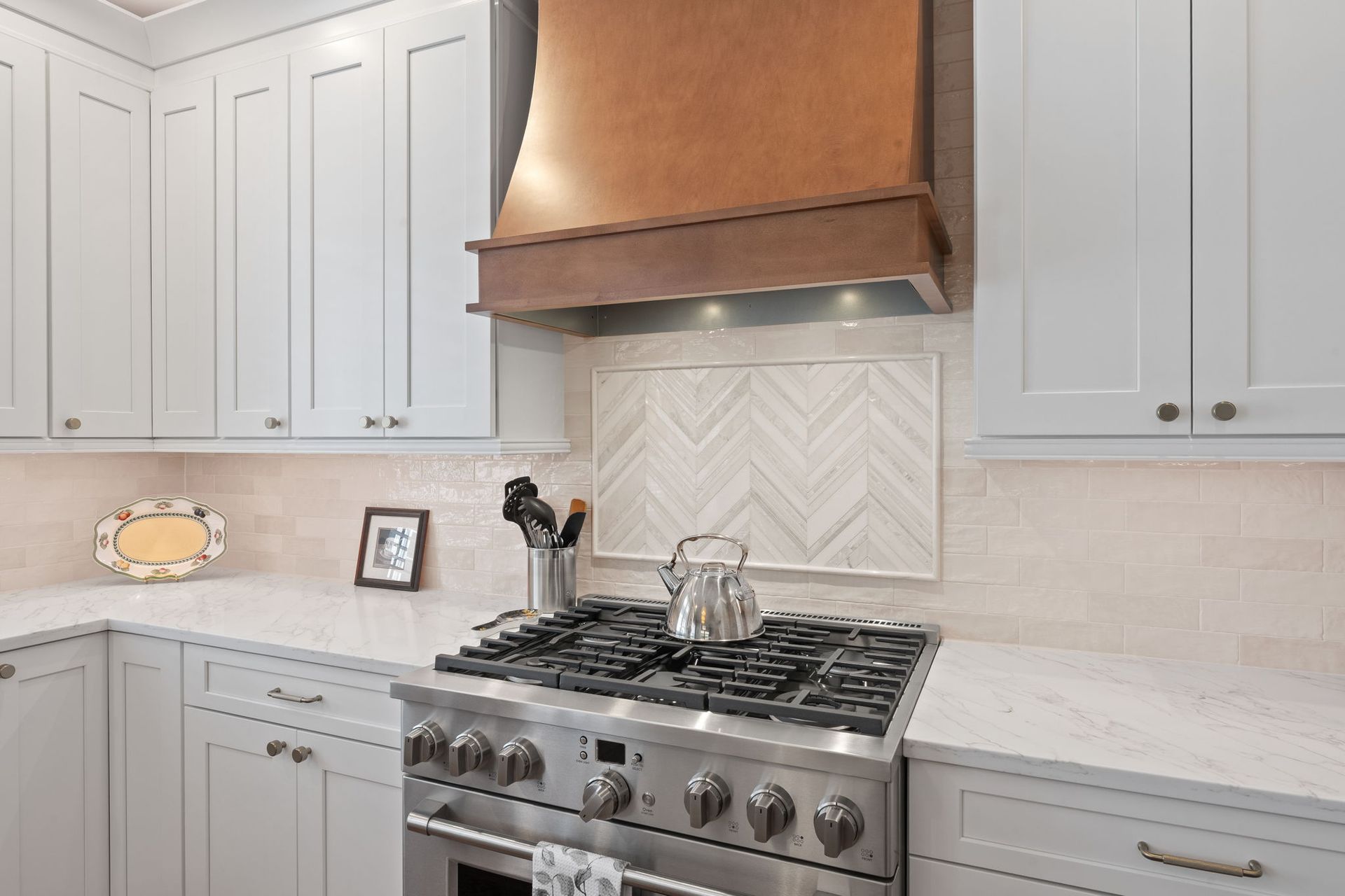 Modern white kitchen with stainless steel stove and copper range hood In Bucks County PA