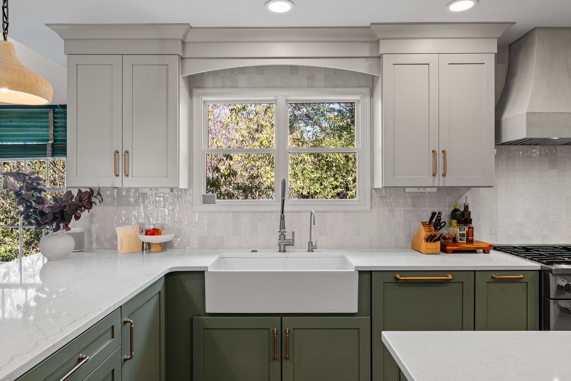 Modern kitchen with white and olive cabinets, marble countertops, and a window over the sink in Bucks County PA