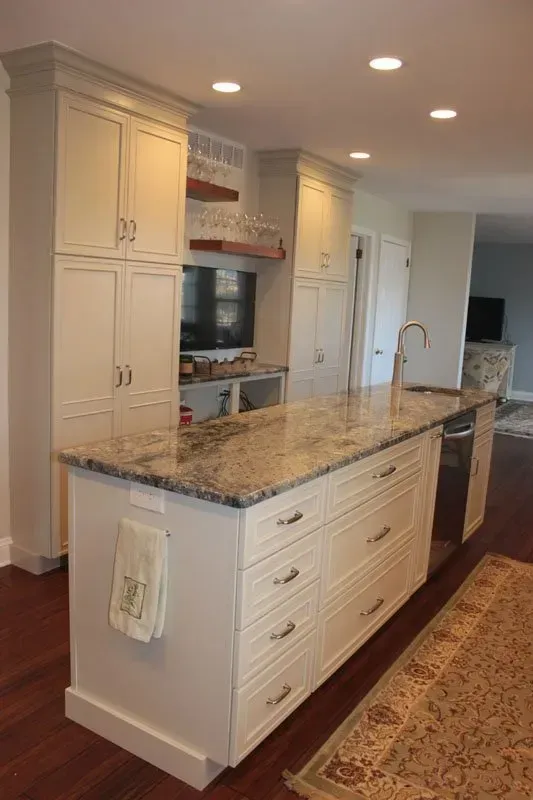 Bright kitchen island with granite countertop, white cabinets, recessed lighting, and hardwood floors In Bucks County PA