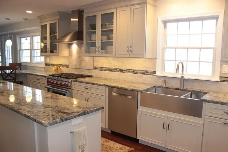 Bright modern kitchen with white cabinets, granite island, stainless appliances, and a large window over the sink In Bucks County PA