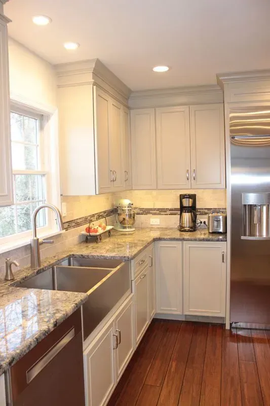 Bright kitchen with white cabinets, granite counters, stainless fridge, and hardwood floor In Bucks County PA