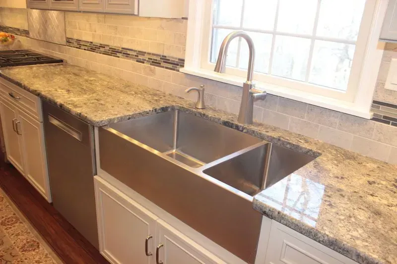 Modern kitchen with granite countertop and stainless double sink under a window In Bucks County PA