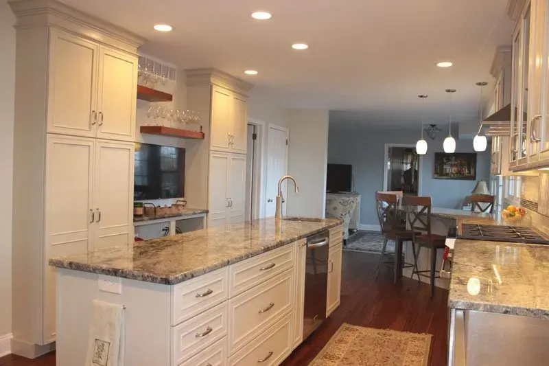 Bright kitchen with white cabinets, granite island, and view into dining area and living room In Bucks County PA