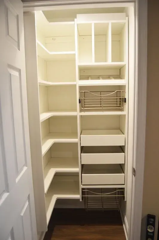 Built-in walk-in closet with shelves, drawers, and hanging storage in a white hallway In Bucks County PA