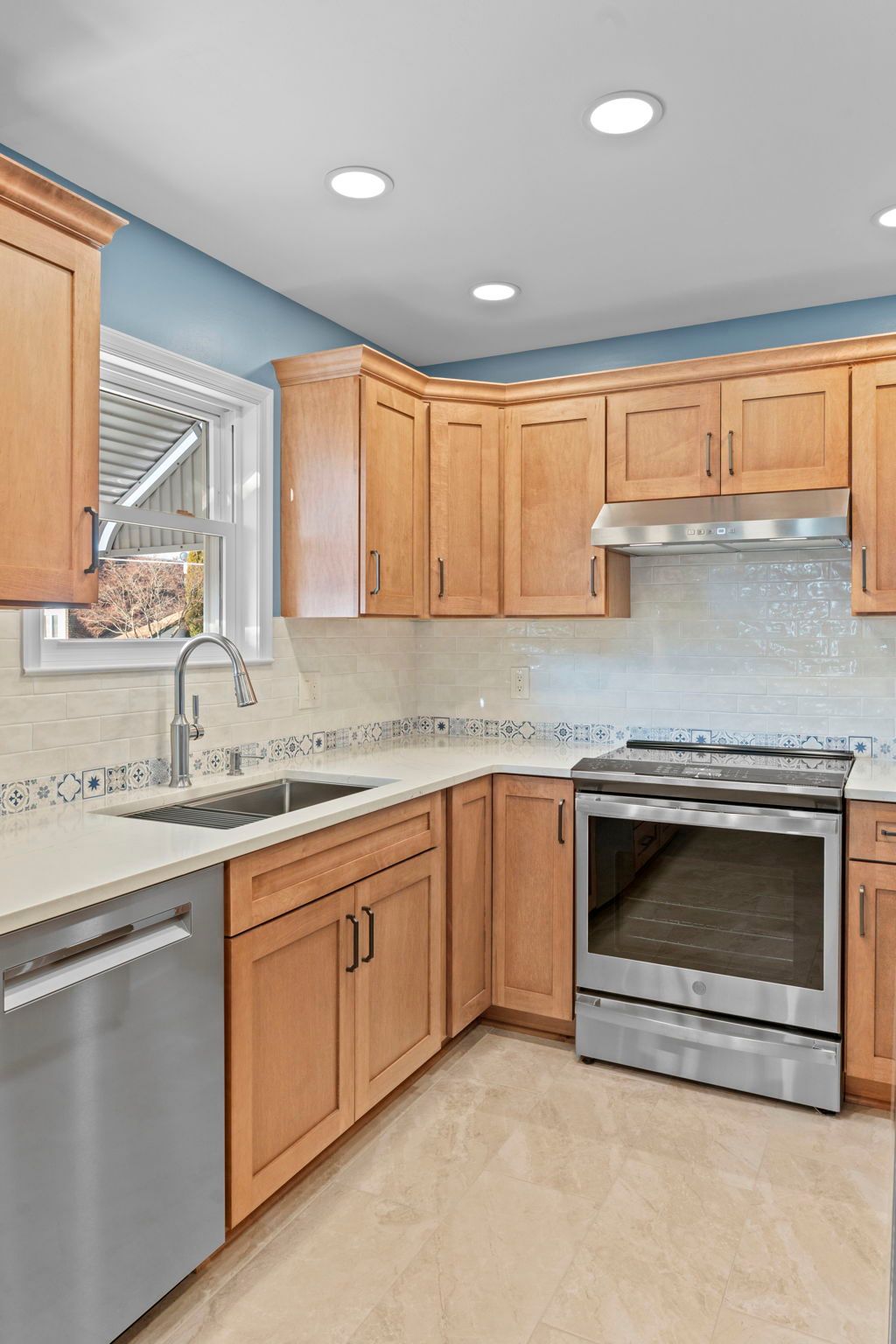 Bright kitchen with wood cabinets, stainless steel appliances, white counters, and recessed ceiling lights In Bucks County PA