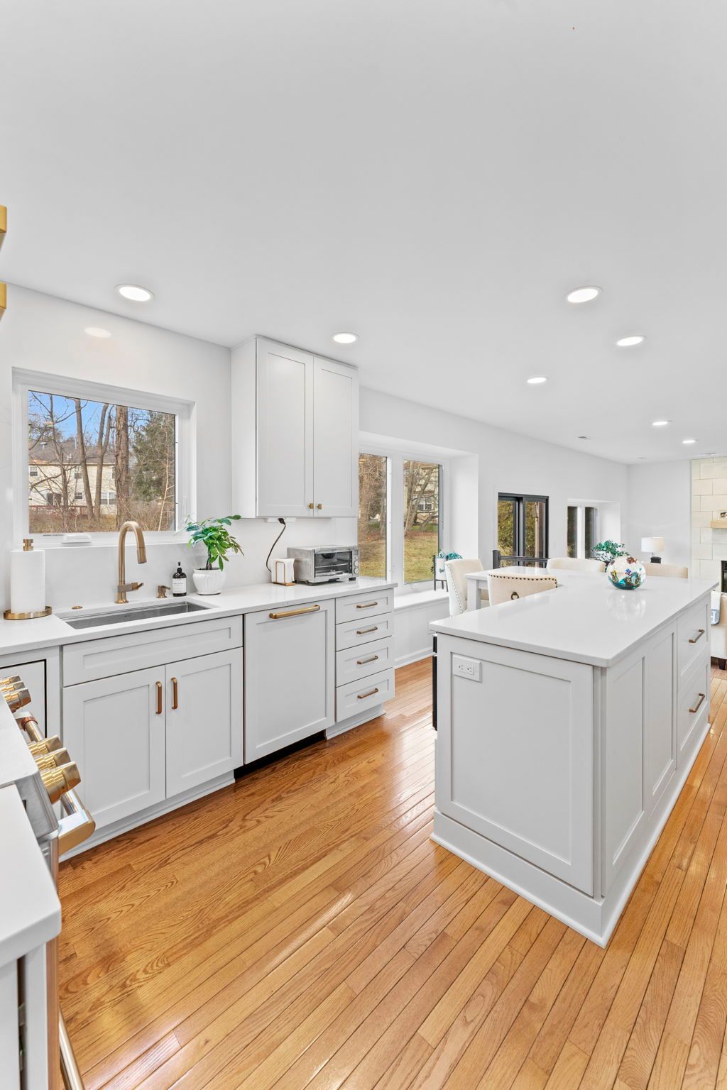 Bright modern white kitchen with island, hardwood floors, and large windows letting in natural light In Bucks Country PA