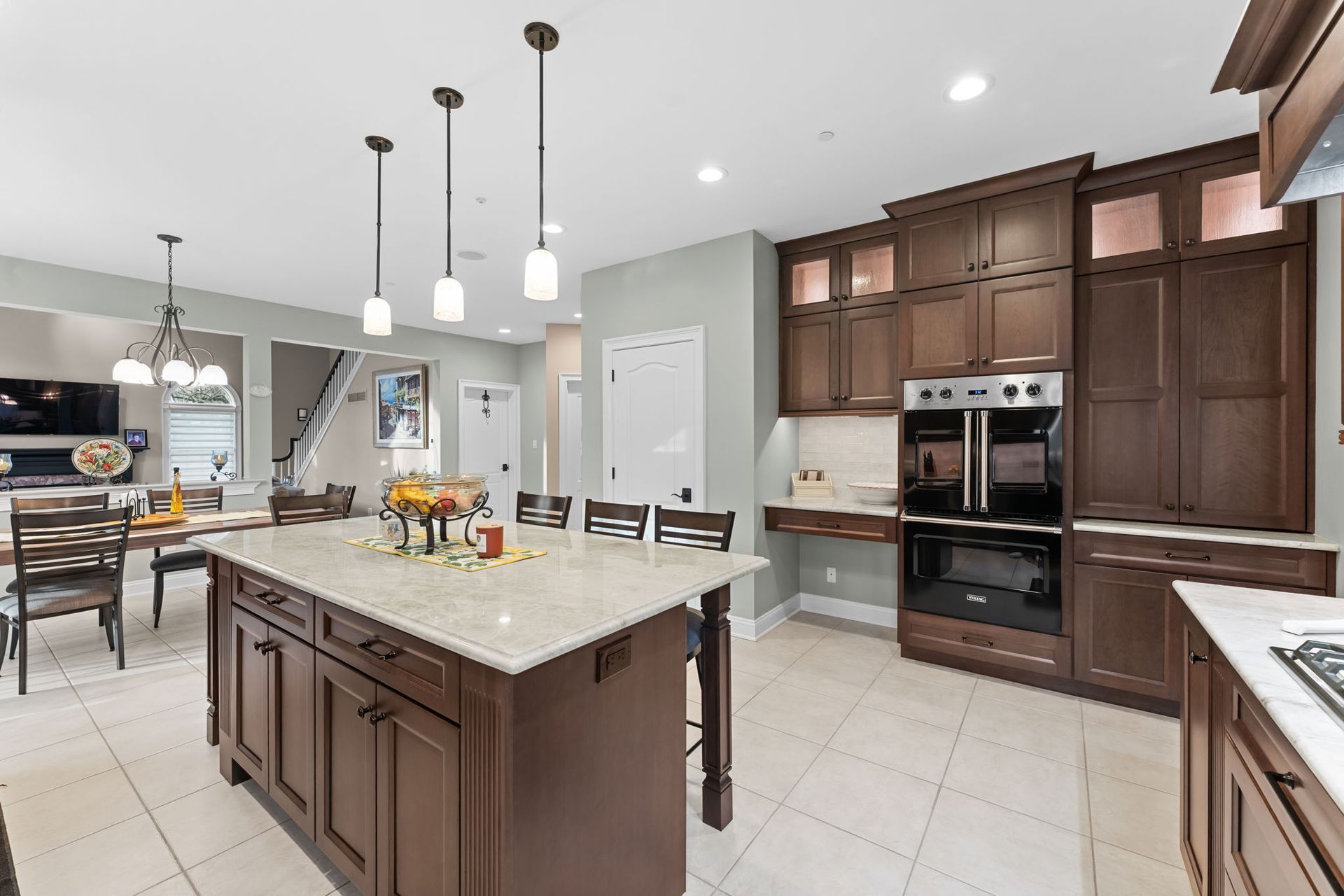 Bright modern kitchen with island, pendant lights, dark wood cabinets, and stainless steel appliances In Bucks Country PA