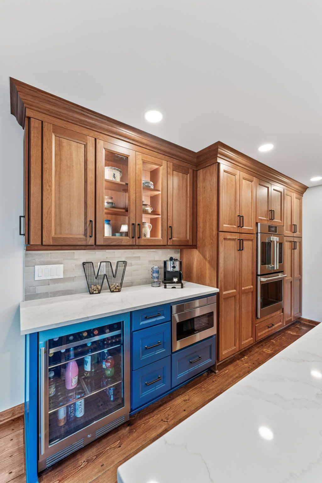 Wood-paneled kitchen with blue under-counter beverage coolers, built-in oven, and white countertop In Bucks County PA