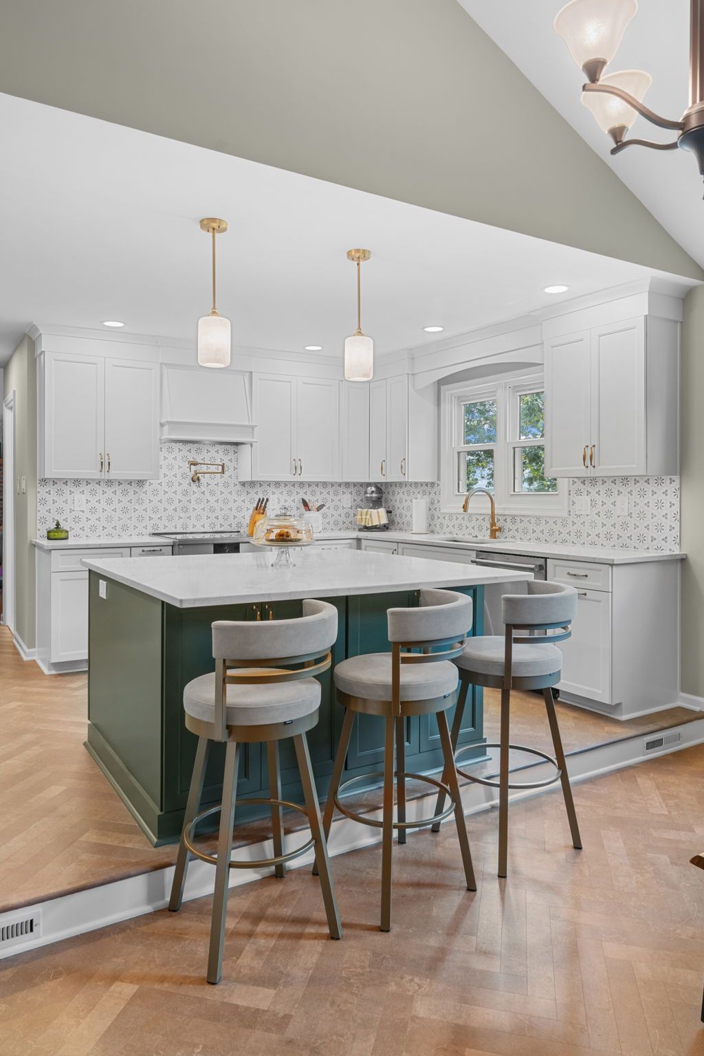 Bright white kitchen with gray island, three stools, pendant lights, and mosaic tile backsplash In Bucks County PA