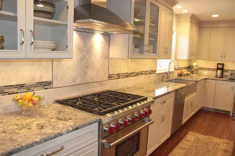Bright kitchen with granite counters, stainless stove, white cabinets, and warm wood floors In Bucks County PA