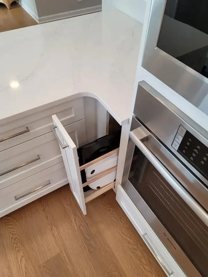 Built-in kitchen corner drawers open beside a stainless steel oven under a white countertop  In Bucks County PA