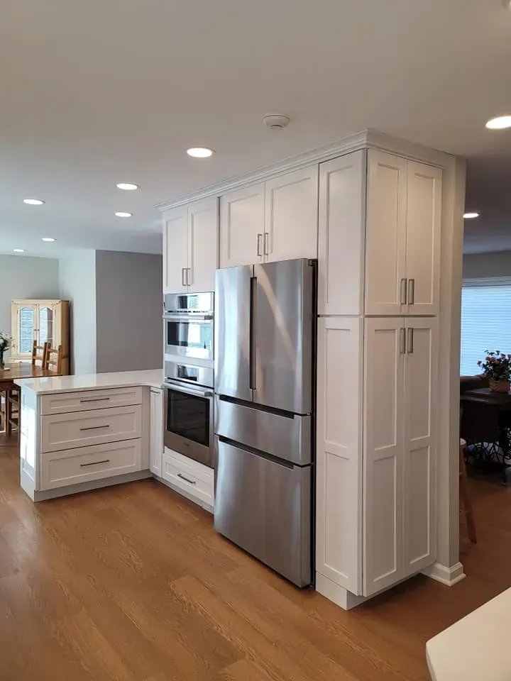 Modern kitchen with white cabinets, stainless steel appliances, and warm wood floors  In Bucks County PA