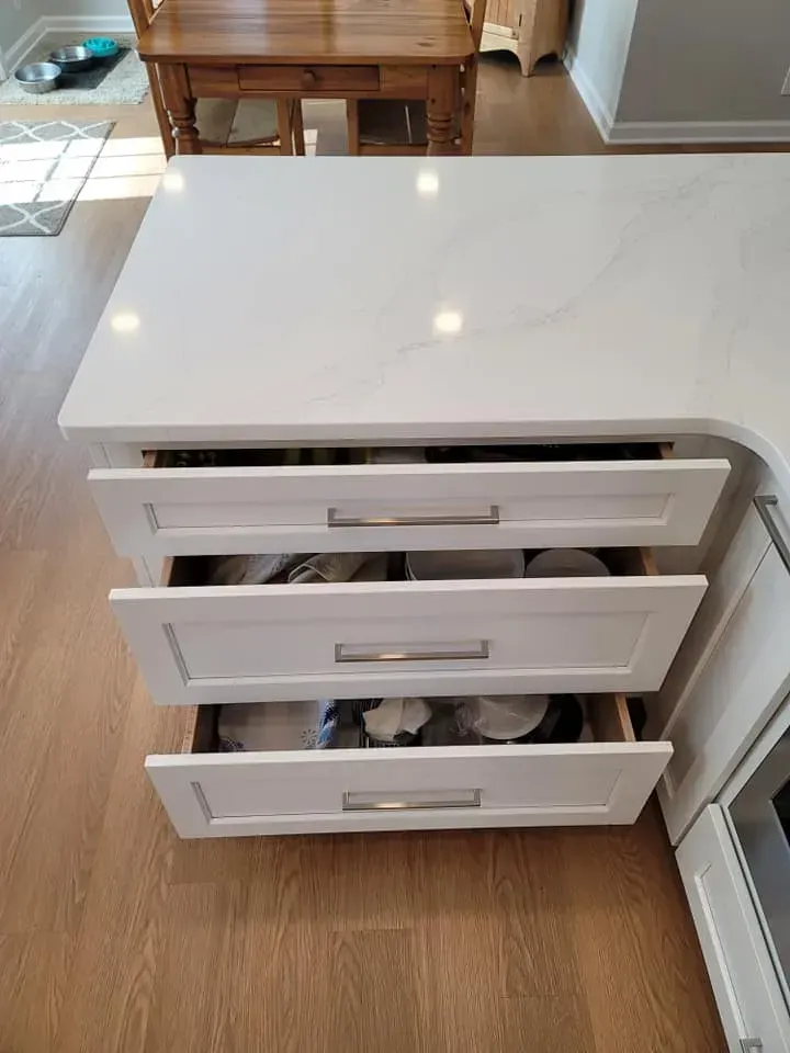 White kitchen island with three open drawers on a wooden floor in a bright room  In Bucks County PA