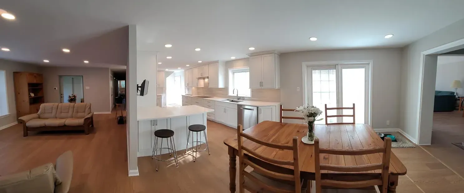 Bright open-plan kitchen and dining area with wood floors, white cabinets, and a living room in the background  In Bucks County PA