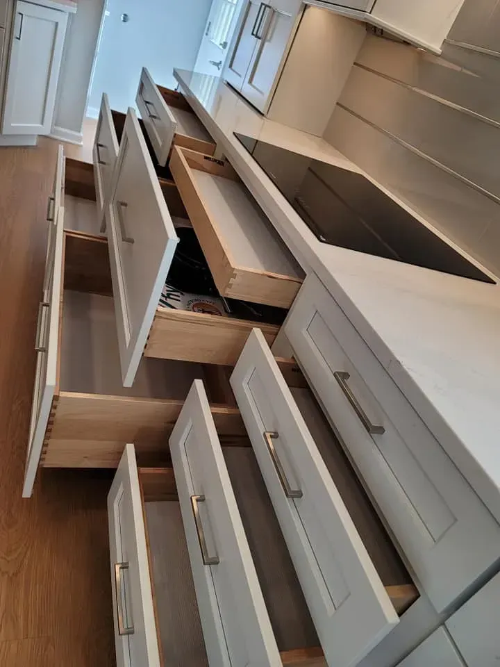 Open kitchen drawers and cabinets with white fronts and dark wood countertops, viewed at an angle In Bucks County PA