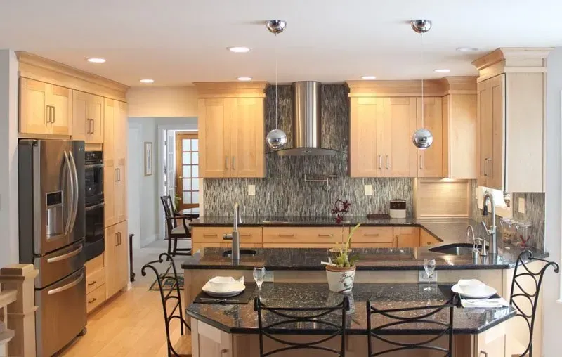 Modern kitchen with light wood cabinets, stainless steel appliances, granite island, and bar stools In Bucks Country PA