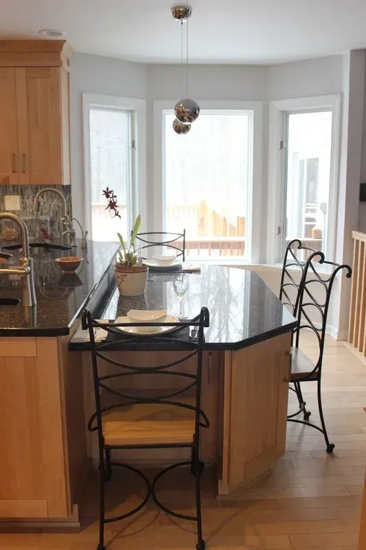 Bright kitchen with a black island, metal barstools, and large windows letting in daylight In Bucks Country PA