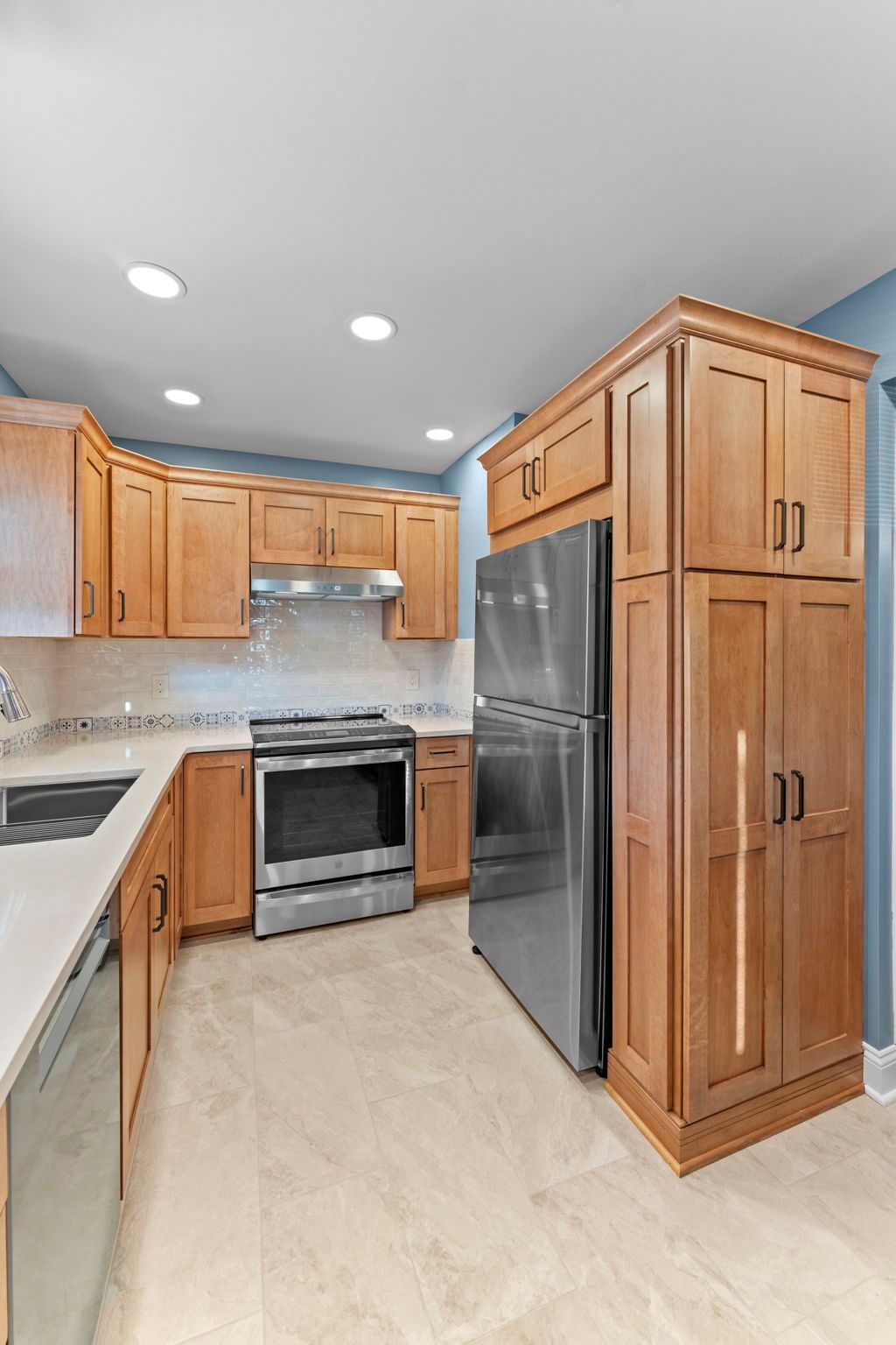 Modern kitchen with wooden cabinets, stainless steel appliances, and light tile floor In Bucks County PA