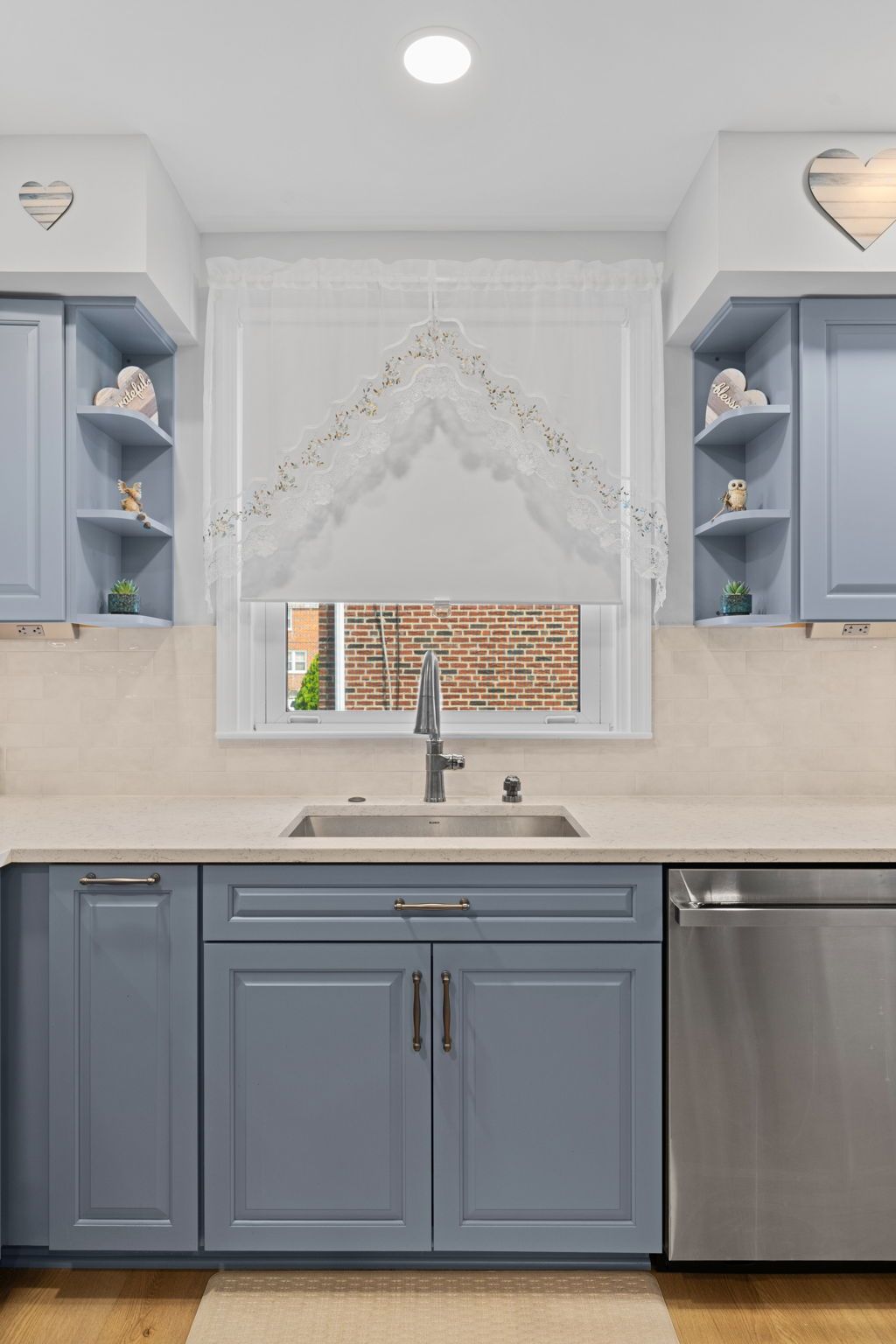 Blue kitchen sink area with white marble backsplash, window, and stainless steel dishwasher In Bucks County PA
