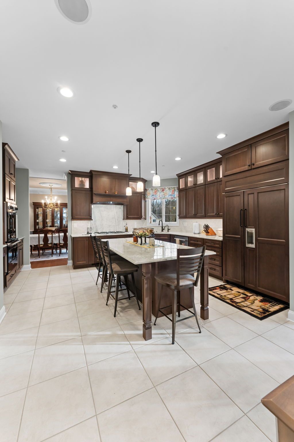 Modern kitchen with large wood cabinets, island seating, and white tile floor In Bucks Country PA