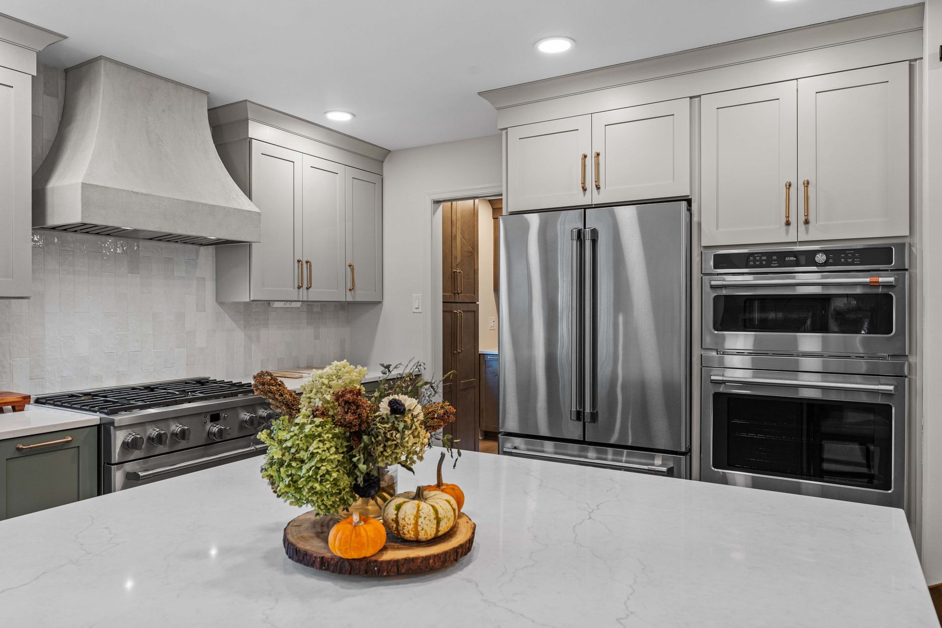 Modern kitchen with stainless steel appliances, white cabinets, and a fruit centerpiece on a large island in Bucks County PA
