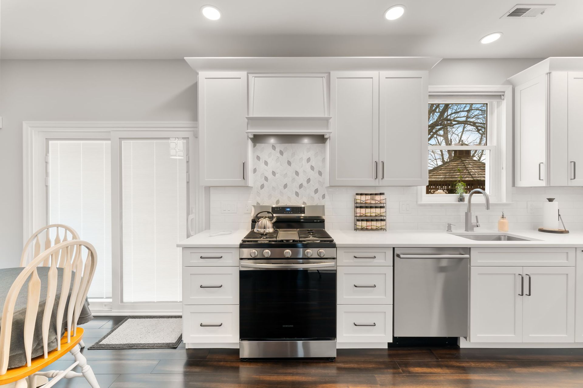 Bright white kitchen with stainless steel appliances, gray cabinets, and dark wood floors  In Bucks County PA