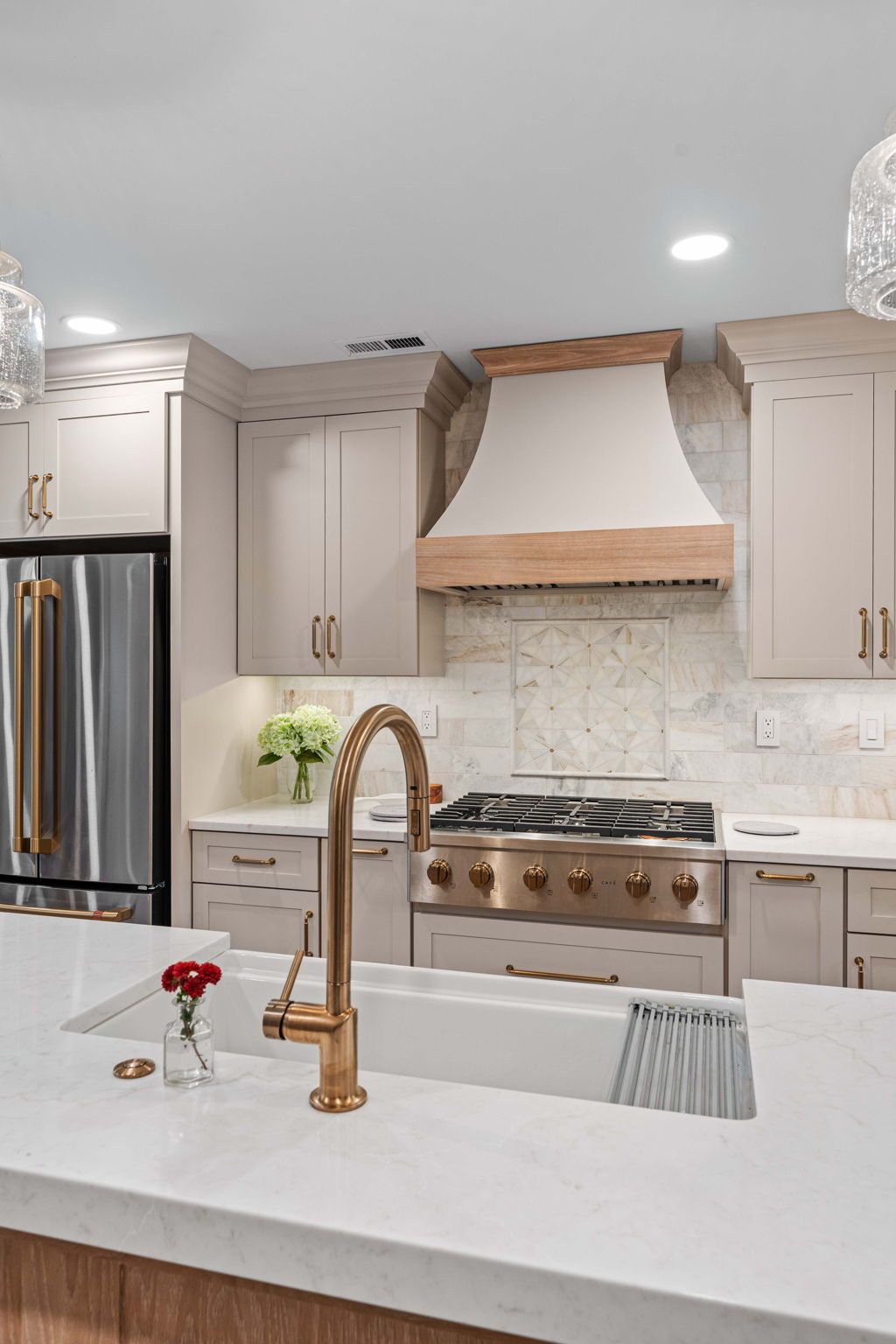 Modern white kitchen with stainless stove, marble backsplash, and copper faucet at island counter in Bucks County PA