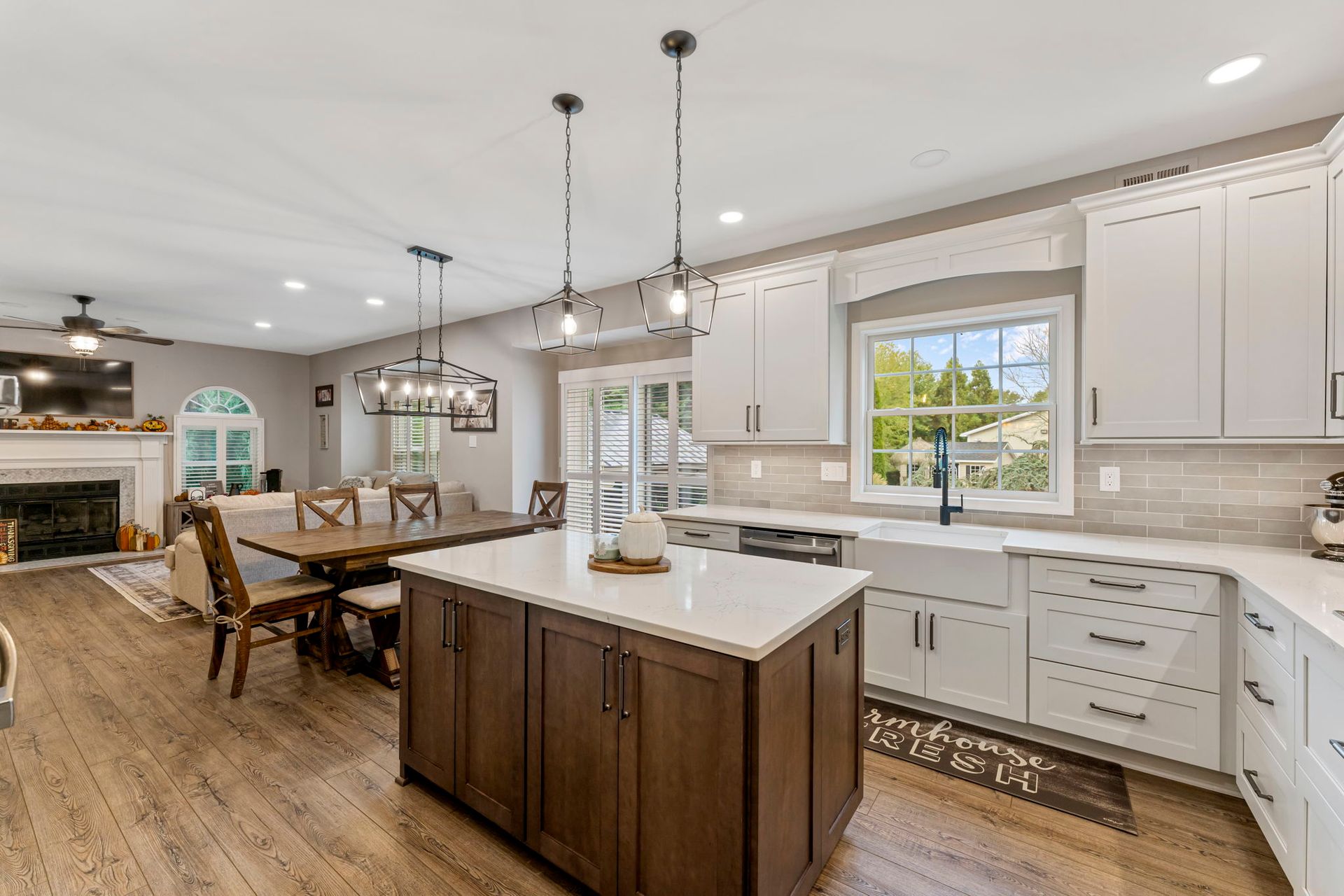 Bright modern kitchen and dining area with island, white cabinets, wood floors, and a fireplace in the background  In Bucks County PA