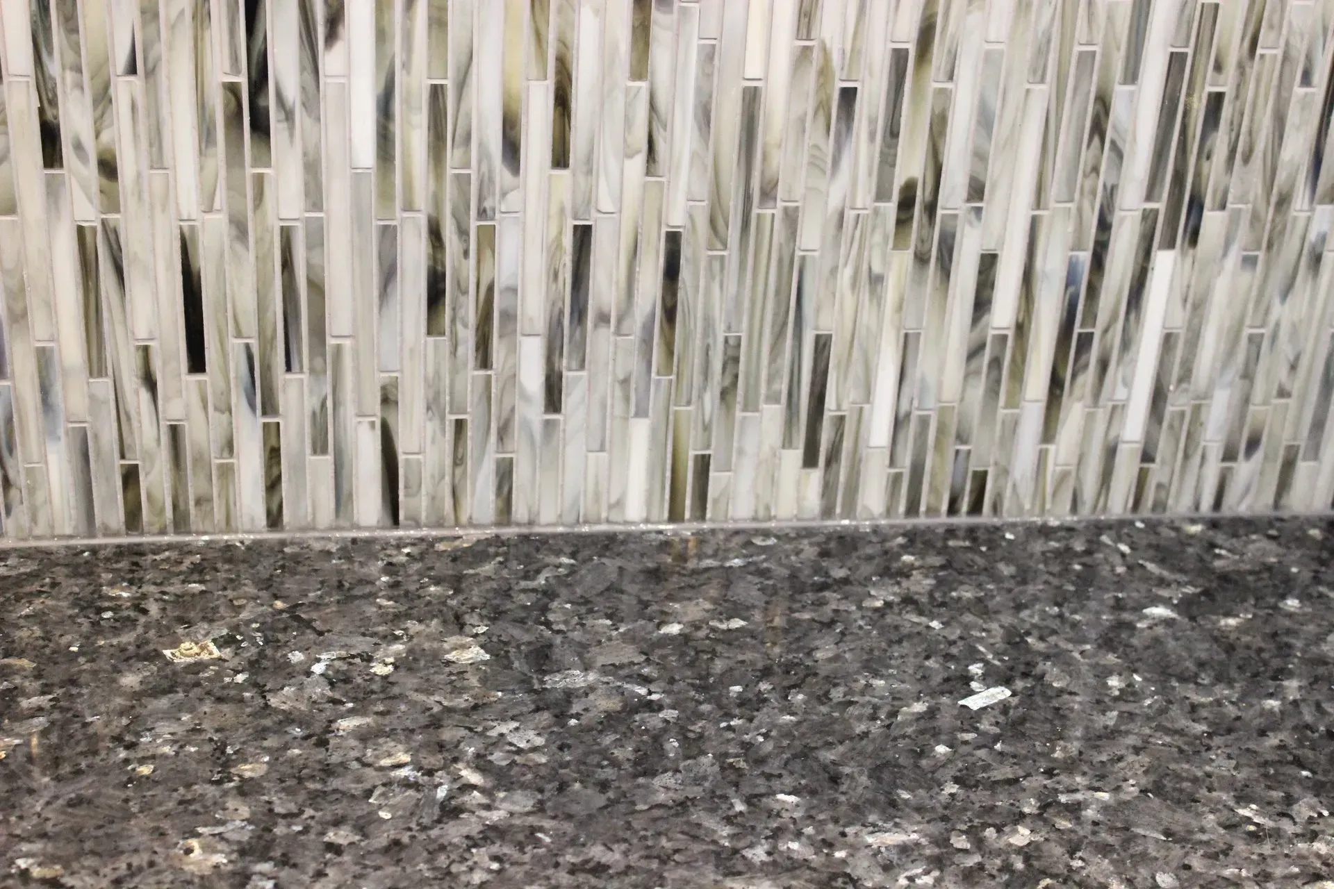 Gray speckled countertop with a light mosaic tile backsplash in the background In Bucks Country PA