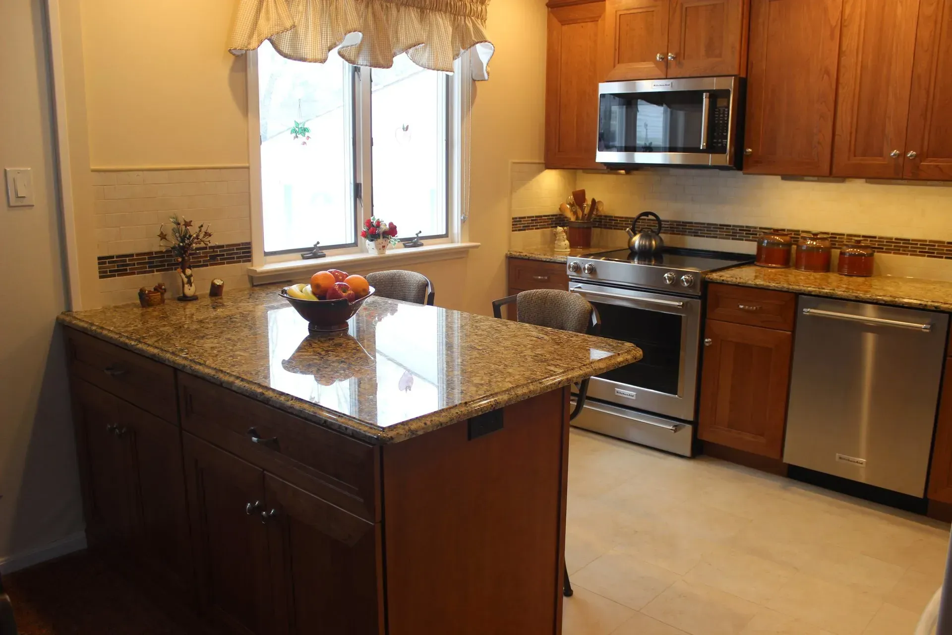 Modern kitchen with wood cabinets, granite island, stainless steel appliances, and a window over the sink  In Bucks County PA