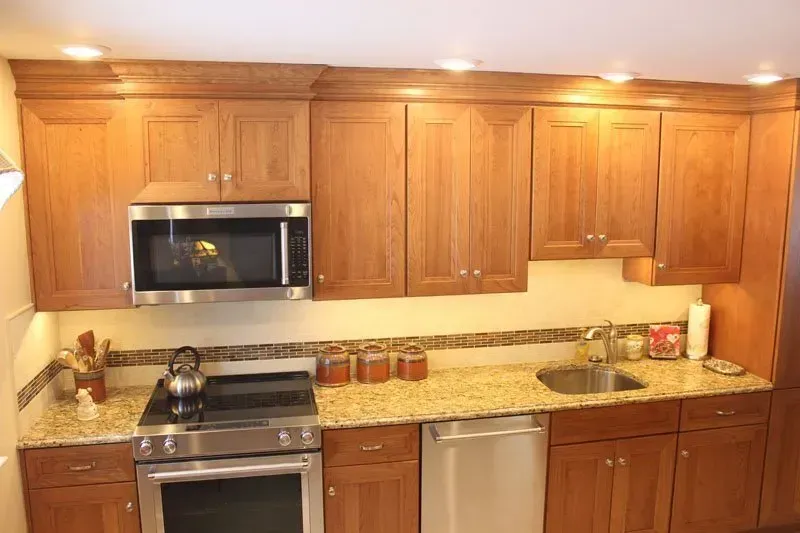 Modern kitchen with wooden cabinets, granite counters, stainless appliances, and warm under-cabinet lighting  In Bucks County PA