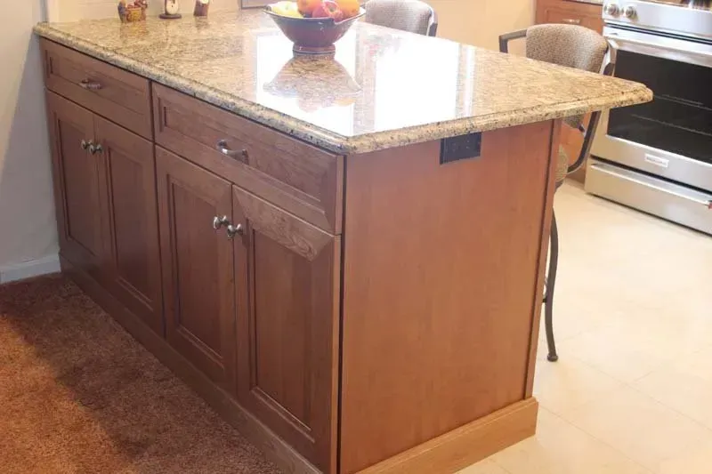 Kitchen island with dark wood cabinets and a speckled granite countertop  In Bucks County PA
