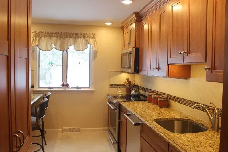 Bright kitchen with wooden cabinets, granite countertops, stainless appliances, and a window over a breakfast nook  In Bucks County PA