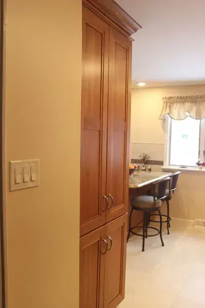 Kitchen hallway with tall wooden cabinets, a bar stool, and a window over the counter  In Bucks County PA