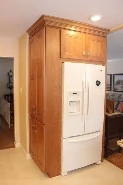 White refrigerator built into a wooden kitchen cabinet with a top freezer and water dispenser  In Bucks County PA