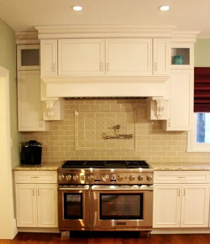 Cream-colored kitchen with stainless steel range, tile backsplash, and white cabinets In Bucks County PA