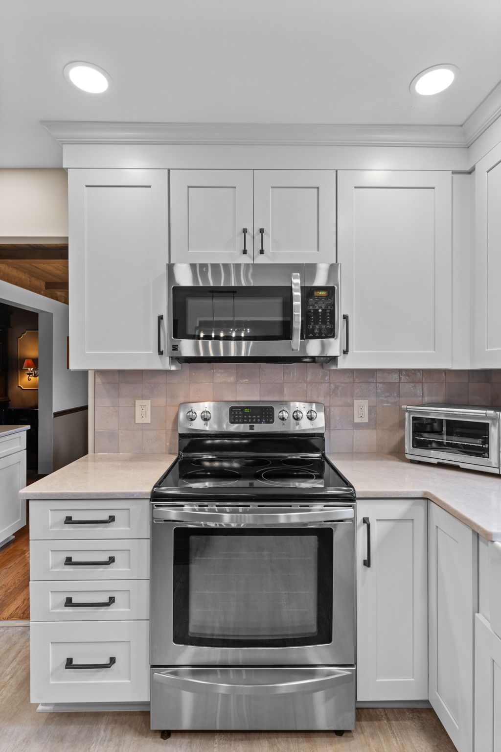 Modern white kitchen with stainless steel stove, microwave, and light tile backsplash  In Bucks County PA