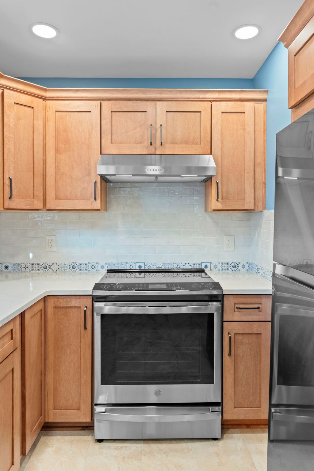 Kitchen with wood cabinets, stainless steel stove, microwave, and blue walls In Bucks County PA
