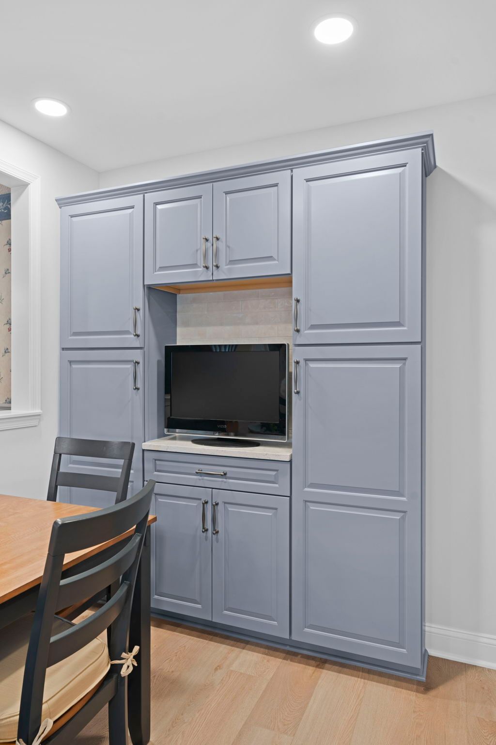 Built-in gray cabinet wall with TV alcove in a bright dining room In Bucks County PA