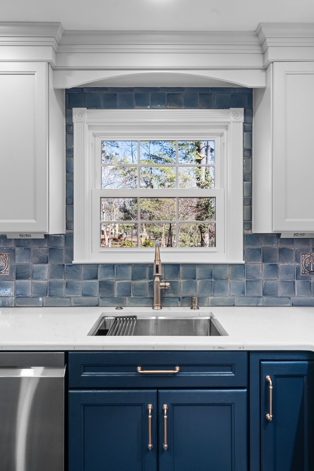 Blue kitchen sink under a window with white cabinets, blue tile backsplash, and stainless steel faucet  In Bucks County PA