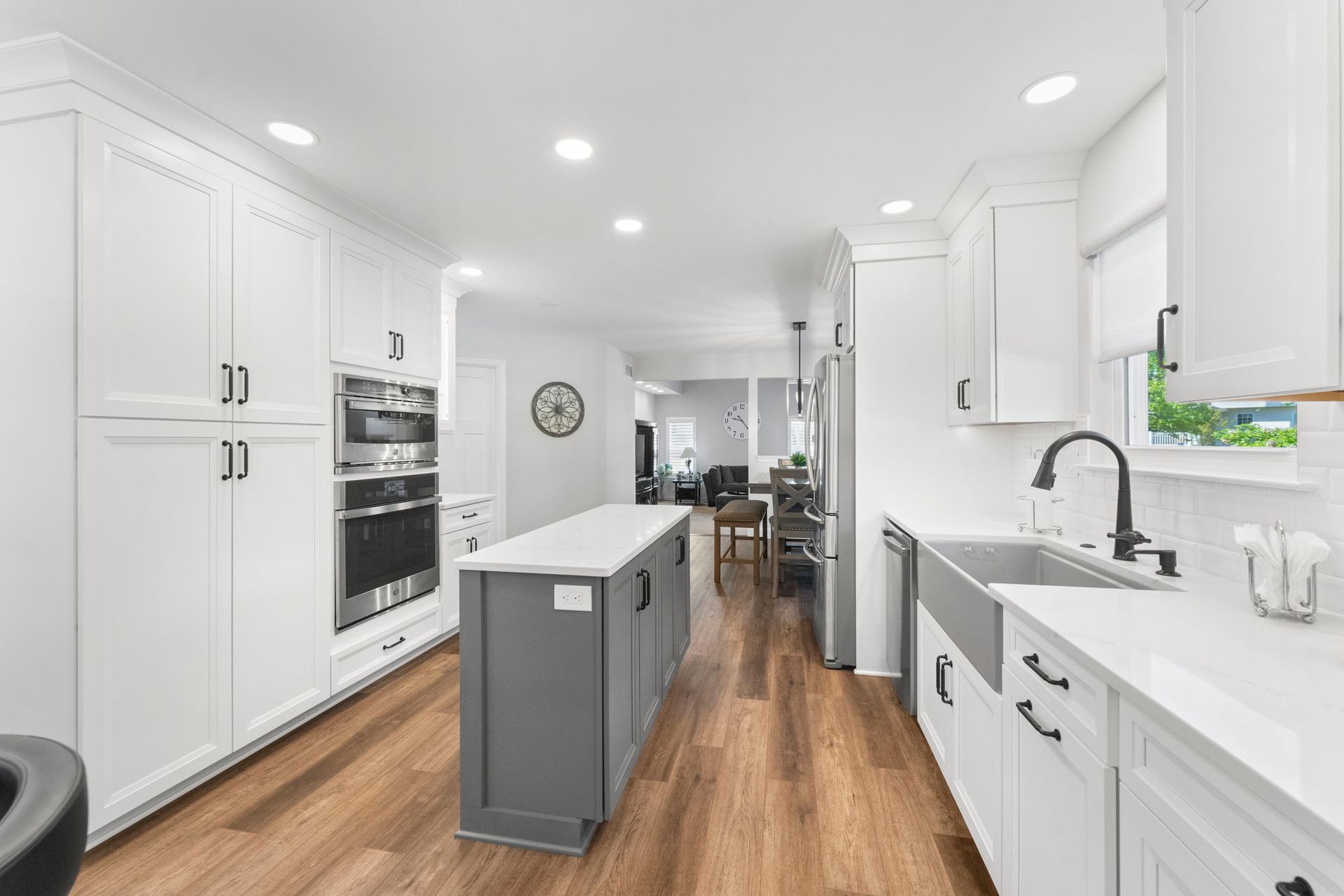 Bright white galley kitchen with wood floors, island, and stainless appliances In Bucks County PA