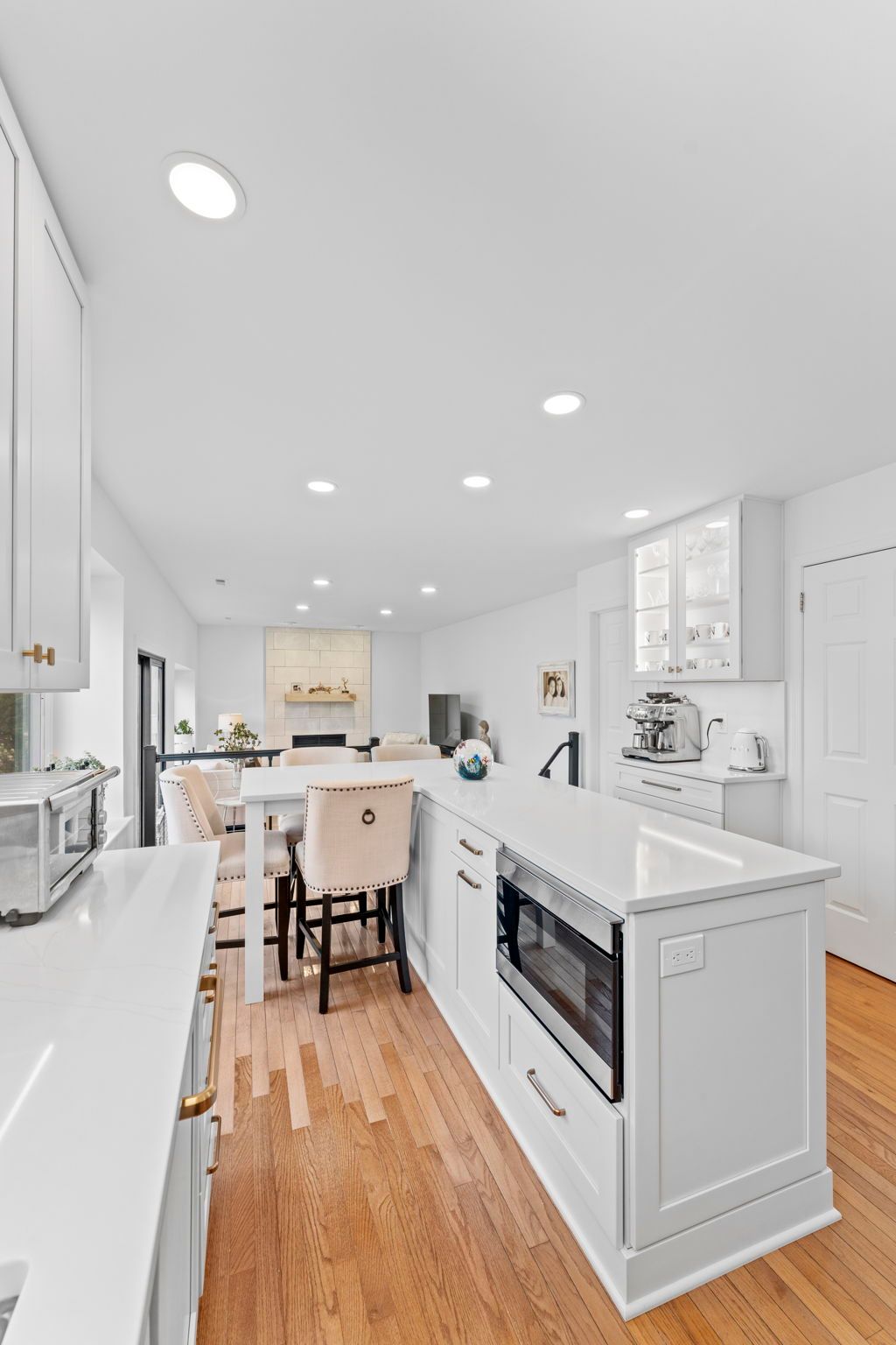 Bright white modern kitchen with island, hardwood floors, and stainless appliances In Bucks Country PA