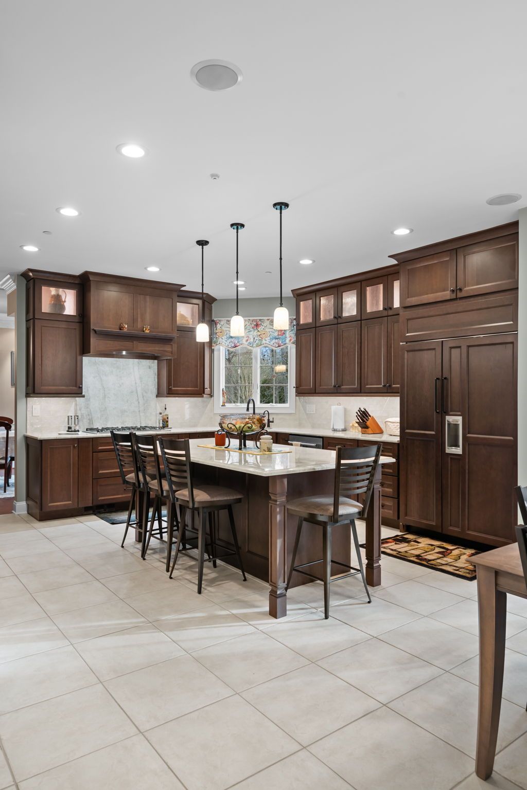 Modern kitchen with dark wood cabinets, central island, pendant lights, and tiled floor In Bucks Country PA