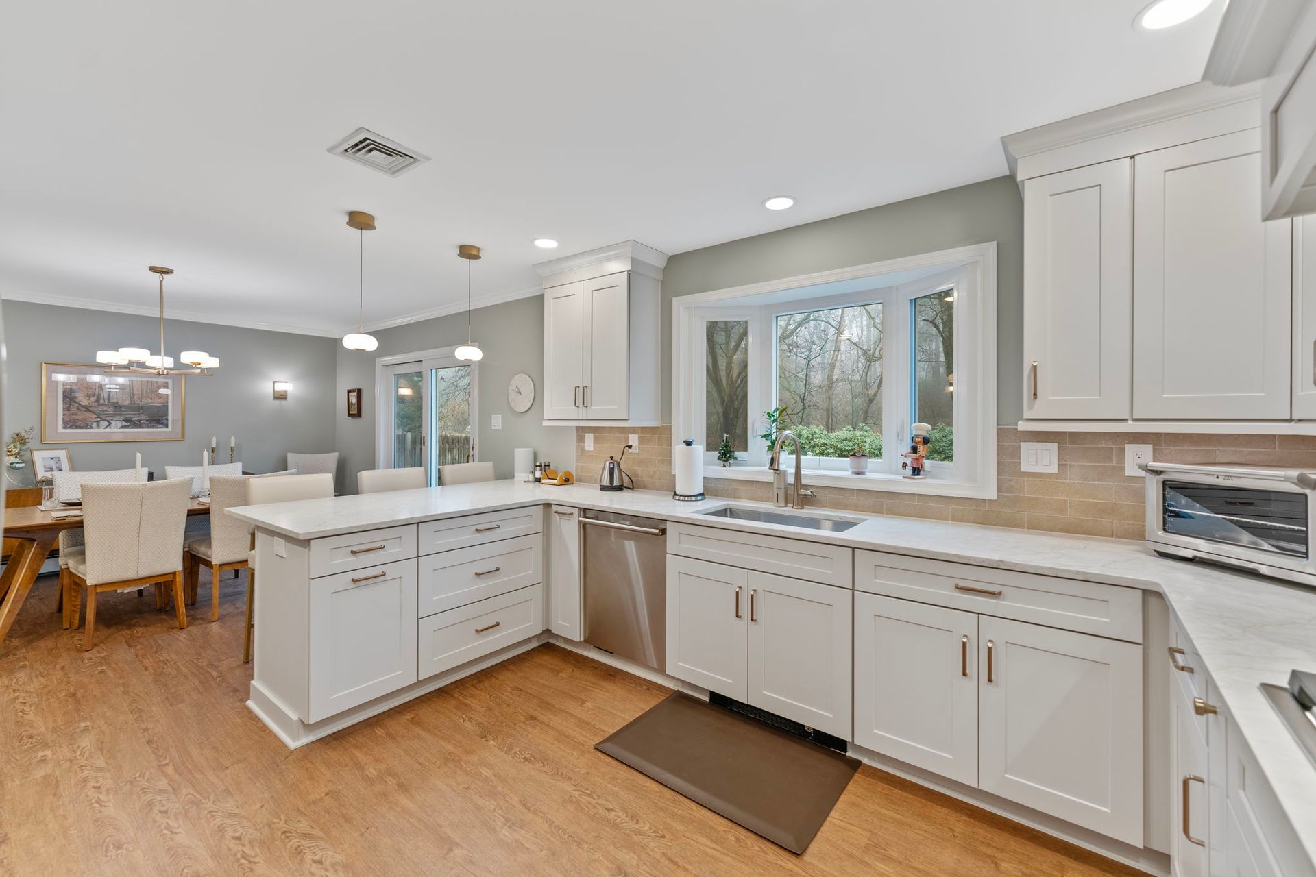 Bright modern kitchen with white cabinets, island, and large window over sink In Bucks County PA