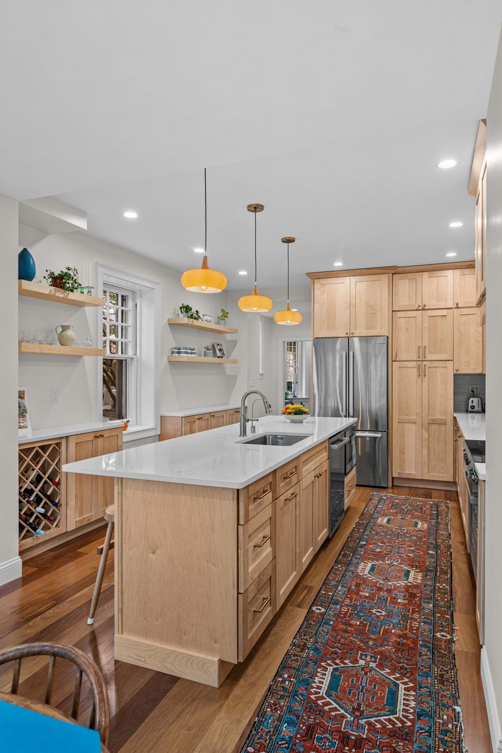 Bright modern kitchen with wood cabinets, large island, pendant lights, and a colorful runner rug In Bucks County PA