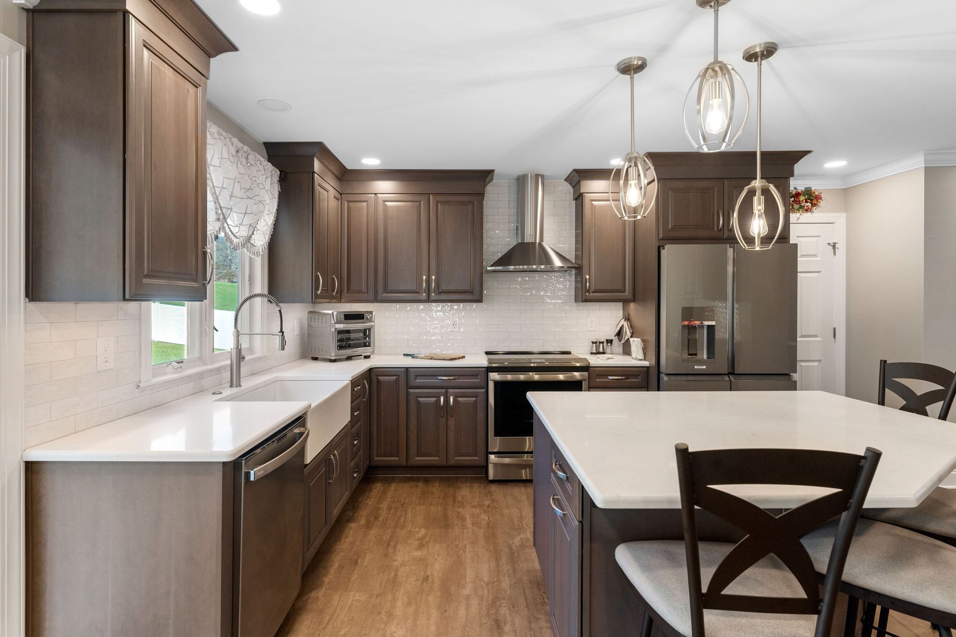 Modern kitchen with dark wood cabinets, white countertops, stainless steel appliances, and a large island in Doylestown PA