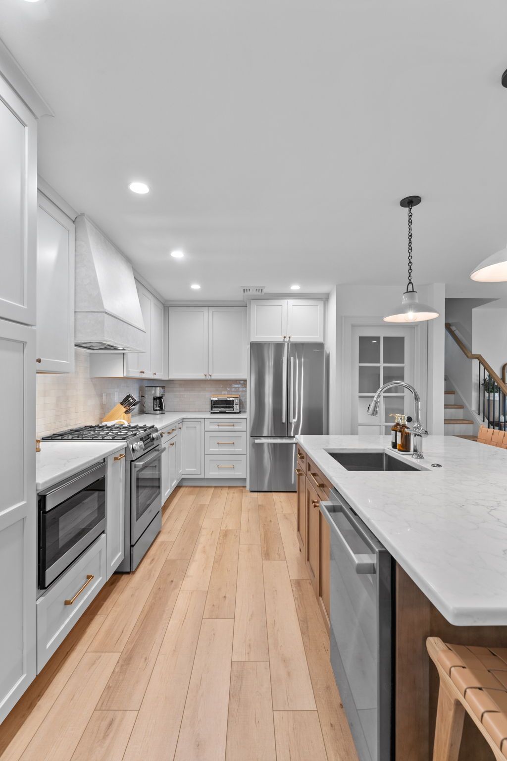 Bright modern kitchen with white cabinets, stainless appliances, and a long island with pendant lights In Bucks County PA