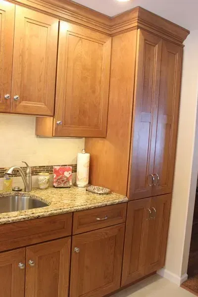 Wooden kitchen cabinets and granite countertop beside a stainless sink and paper towel holder  In Bucks County PA