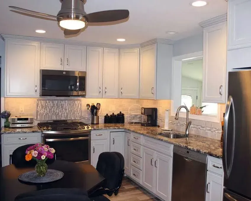 Bright white kitchen with stainless appliances, granite counters, and a round table with flowers In Bucks Country PA