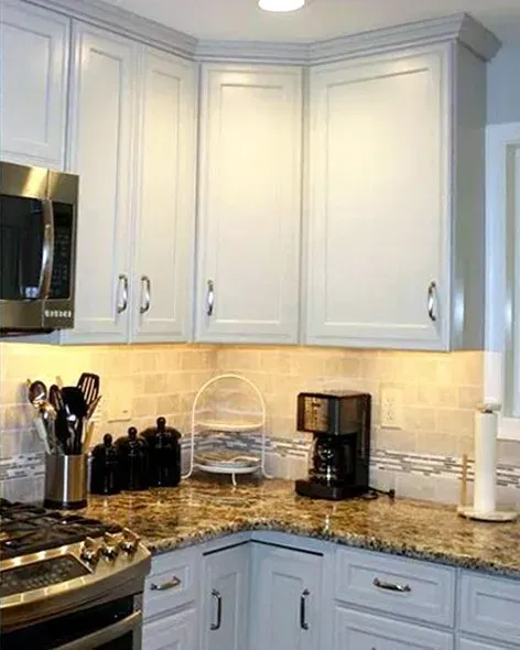Bright kitchen corner with white cabinets, beige backsplash, granite countertop, and coffee maker In Bucks County PA